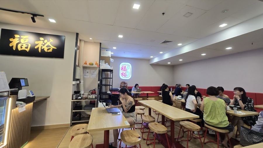 Communal timber tables and stools along the red banquette